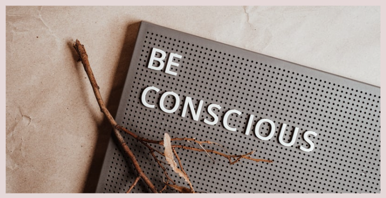 Image of a twig with the words 'be conscious' on a board.