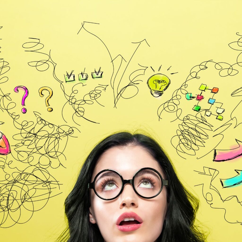 A woman wearing glasses, looking up at drawn squiggles and lightbulb images