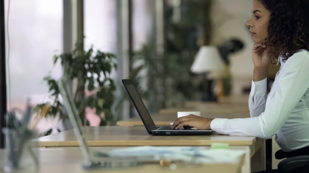 Lady in white shirt sitting at a desk with her hand to her chin and a hand on her laptop.

Adobe Stock: search assistant presenting idea workplace.
